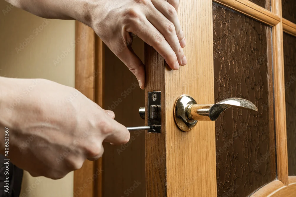 Hands fitting a door handle and lock on a wooden door